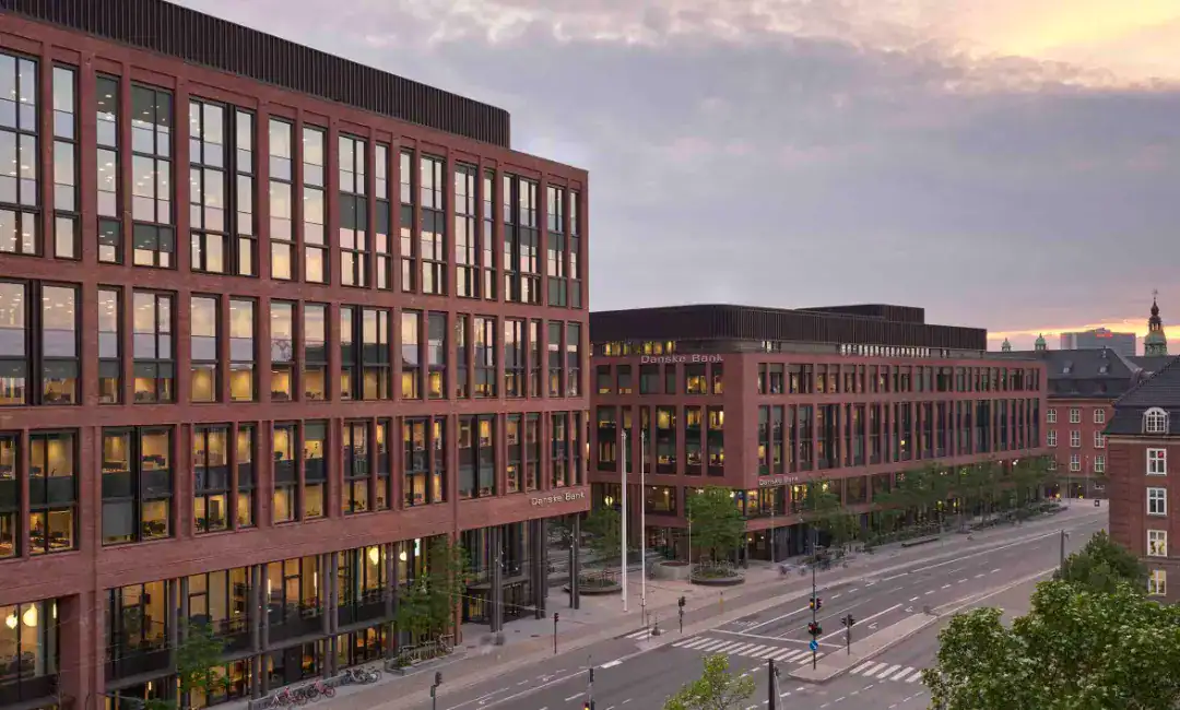 Moderne kontorbygning i København med store vinduer og bymiljø.