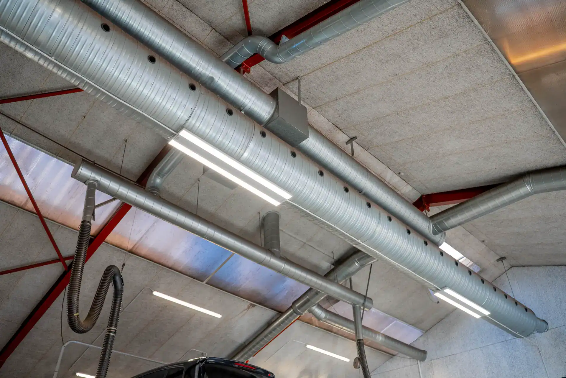 Industrivæg- og loftsinstallationer med ventilationsrør og lys.