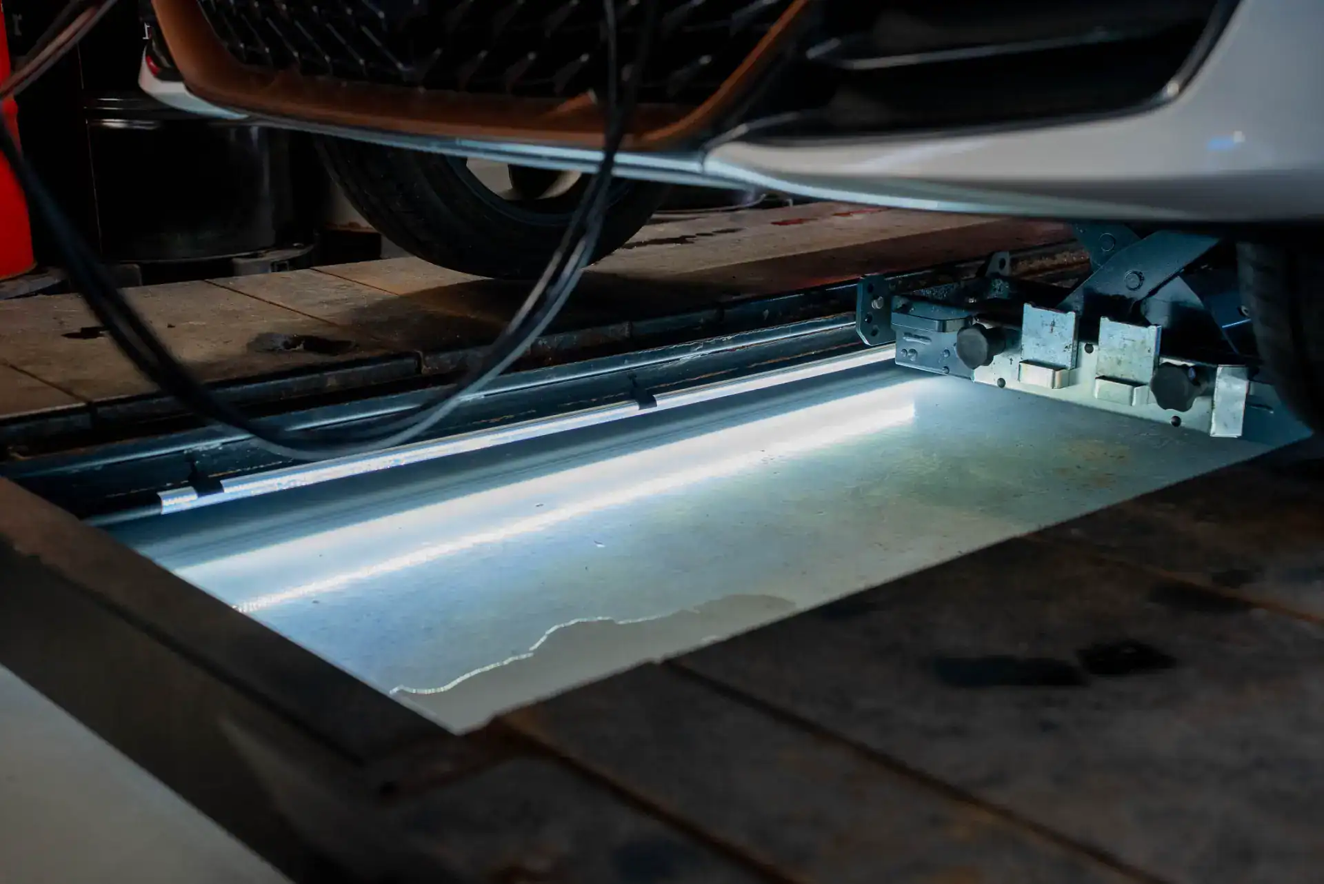 Billede af bilværktøj under bilen, klar til reparation eller inspektion.