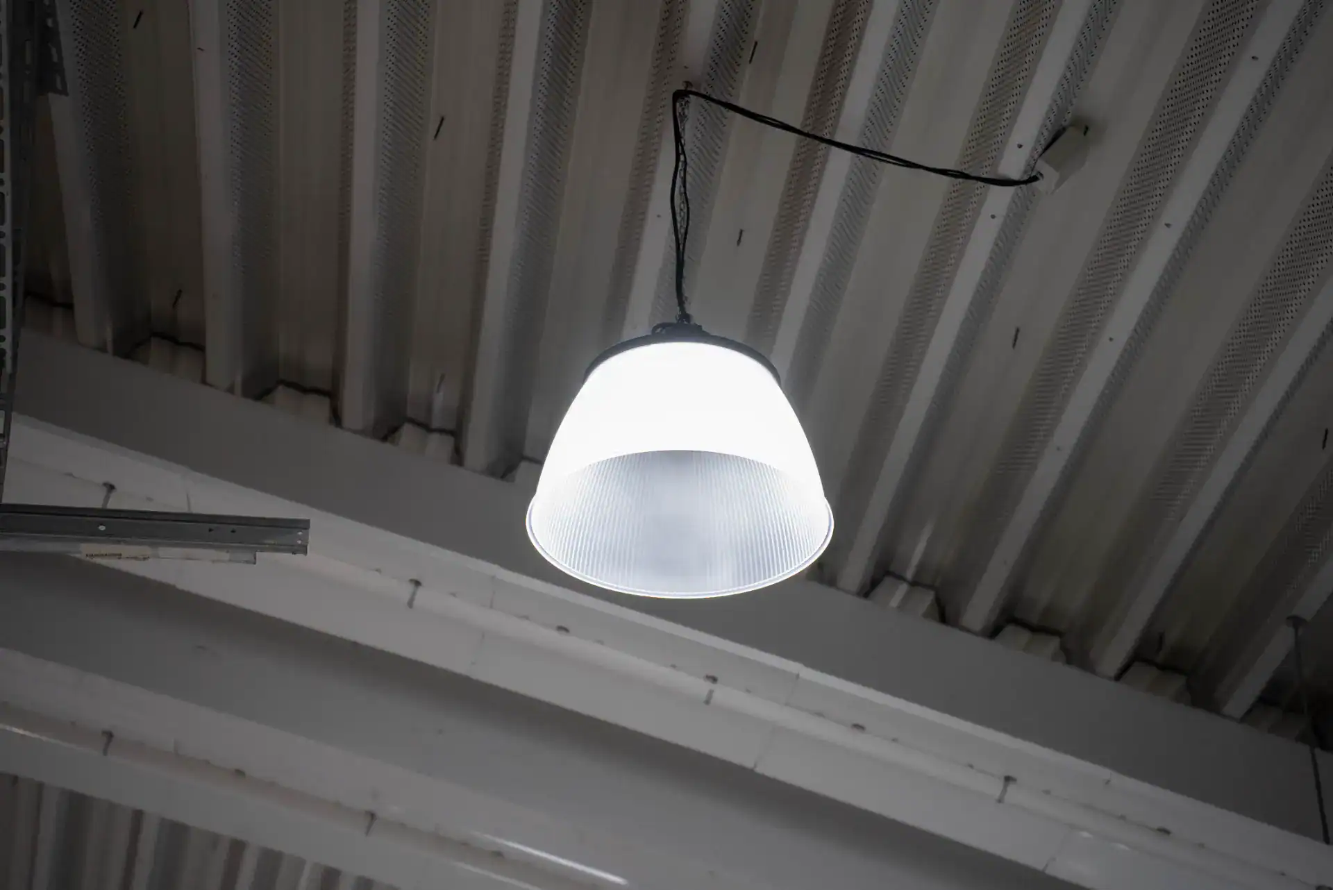 Lyskilde hængende i et industrilager med metalloft.