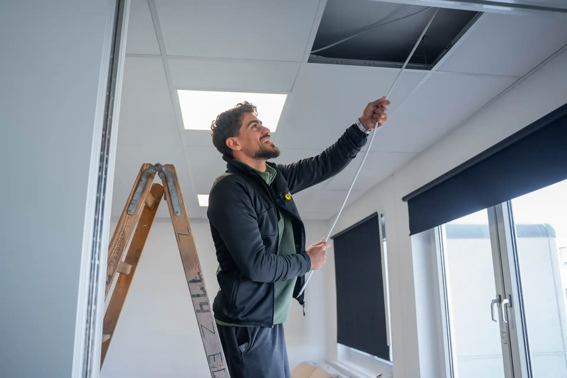 Elektriker installerer loftslys i kontorlokale.
