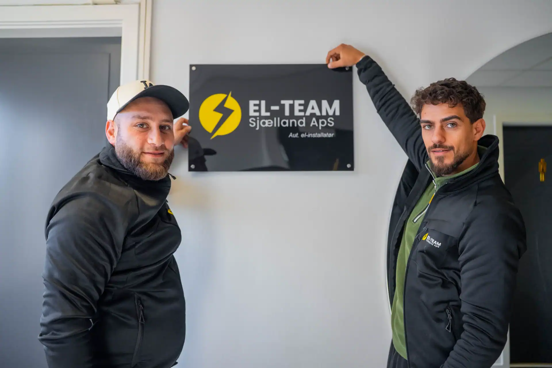 To elektrikere foran El-Team Sjælland ApS skilt, klar til service.