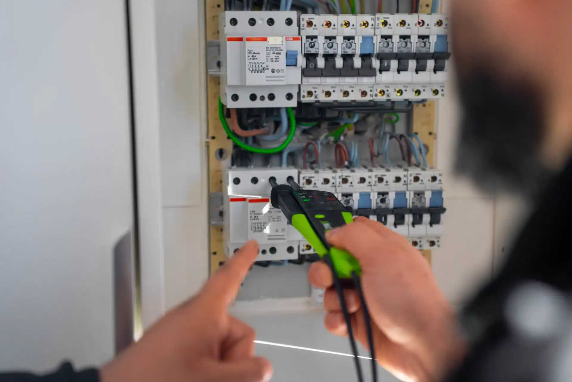 Elektriker arbejder med el-tavle og måler elektrisk strøm.