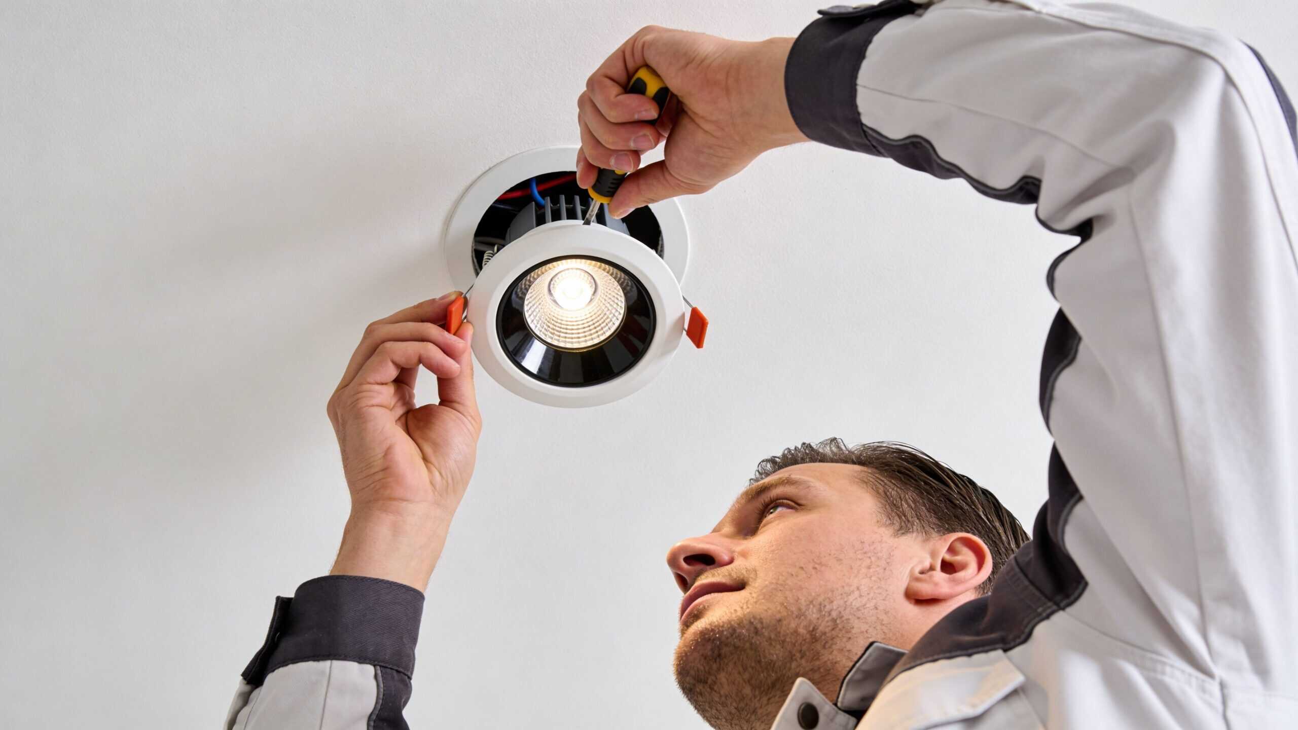 Mand installerer en loftspot med værktøj i et hjem eller kontor.