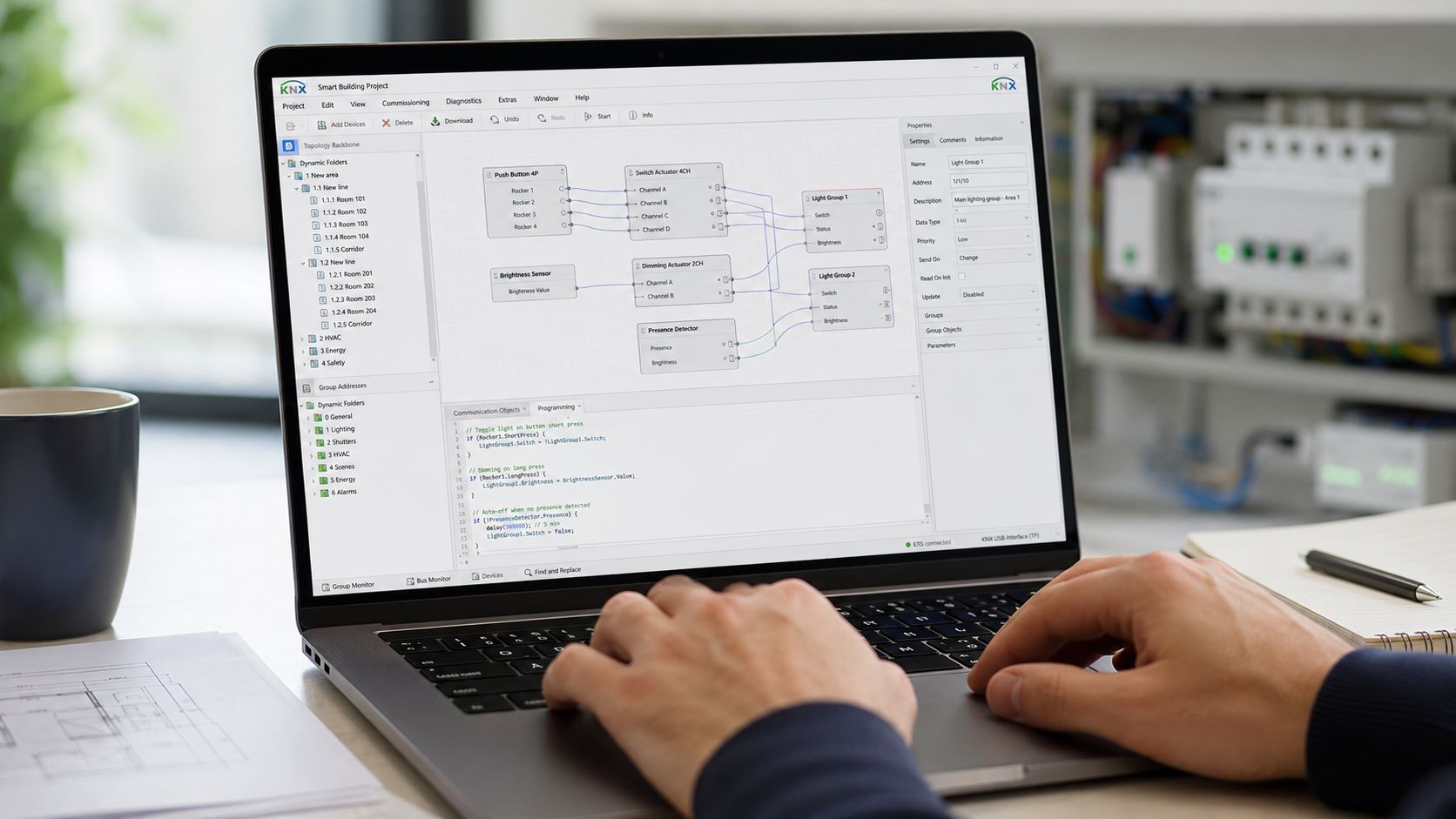 En person programmerer et intelligent bygningssystem ved hjælp af KNX software på en bærbar computer ved et skrivebord.
